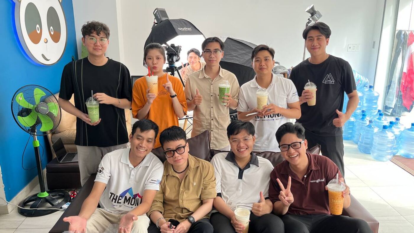 Đội ngũ MONA ngồi cùng nhau trước bức tường gấu trúc tại văn phòng